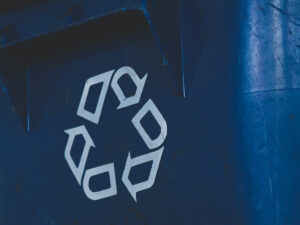 Close up of a white recycling symbol on a blue plastic can