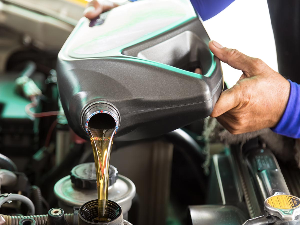 Mechanic refilling oil in car engine